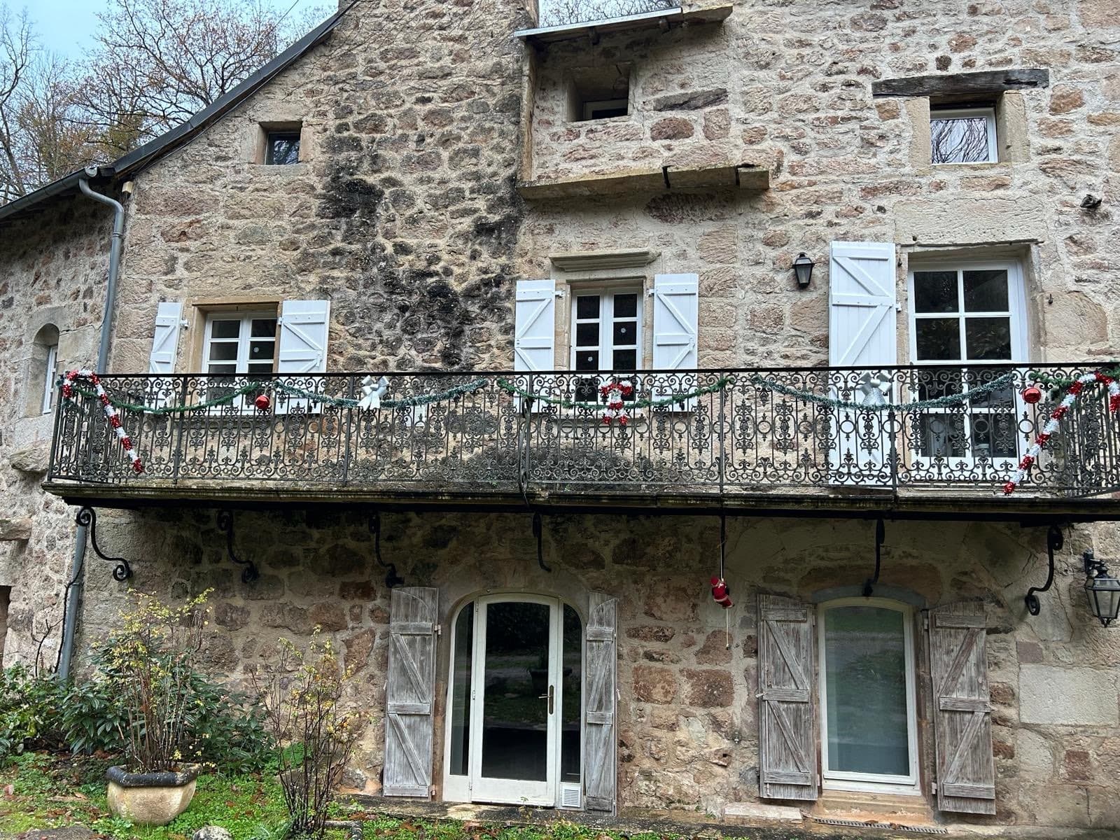 Façade en pierre du moulin avec balcon en fer forgé décoré pour Noël